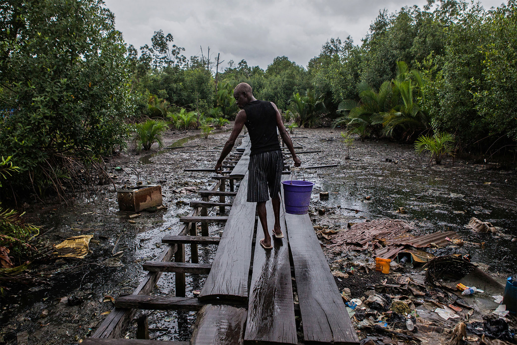 A man walks along the former jetty of Ugborodo, Nigeria, on June 13, 2016. The water in the area is heavily polluted by oil. (Photo by Jane Hahn/New York Times)
