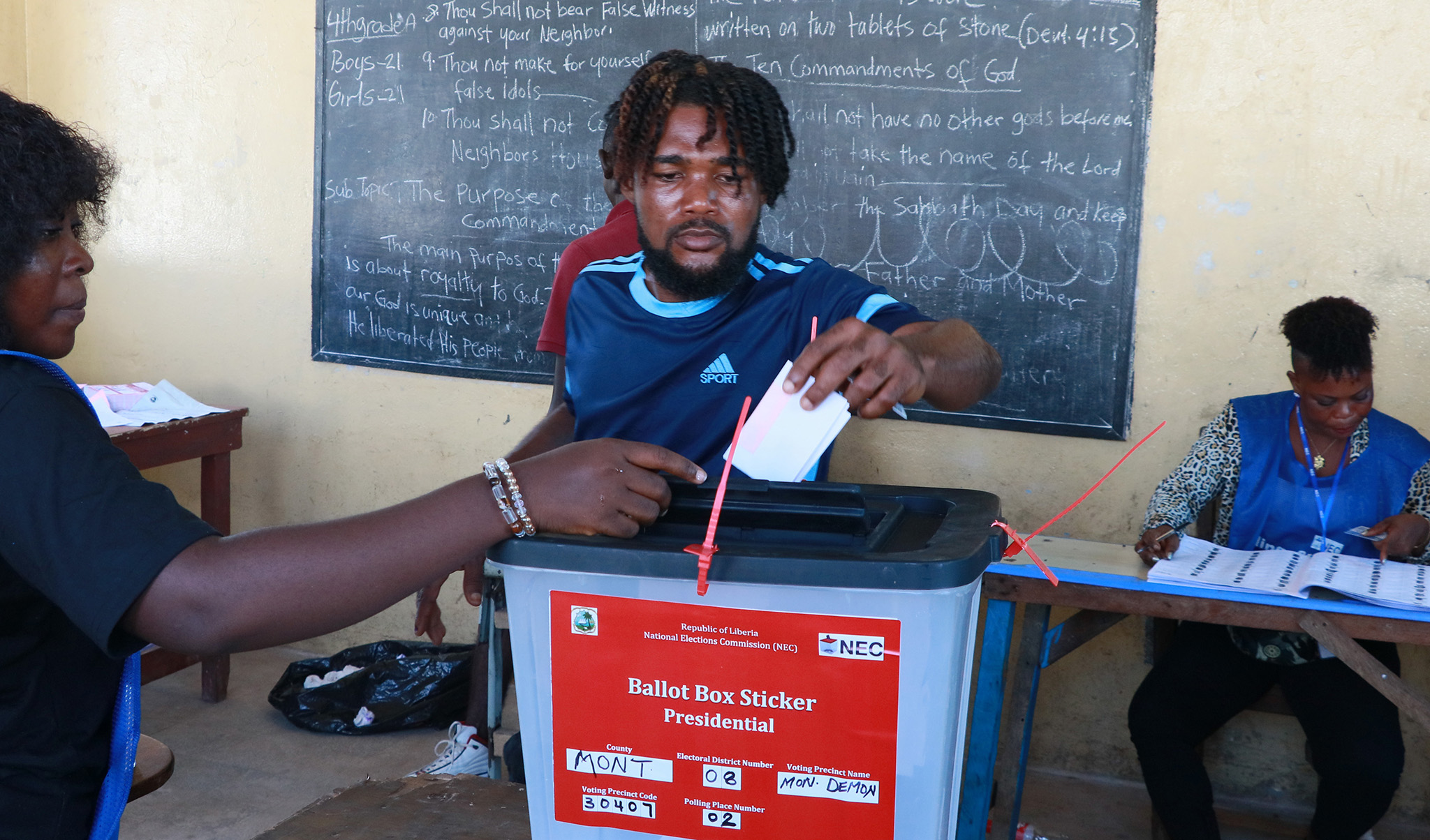 Liberian election workers help a man cast his presidential ballot at a Monrovia school in November. Liberia’s peaceful election and transfer of power could make the country a prodemocracy ‘peer influencer’ in turbulent West Africa. (Flickr/PhotoLiberia)