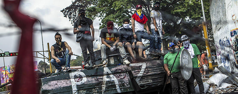 Protesters pose for a portrait atop a vintage tank that they moved from its position on display to use as a barricade in San Cristobal, Venezuela, Feb. 23, 2014. Photo Credit: The New York Times/ Meridith Kohut