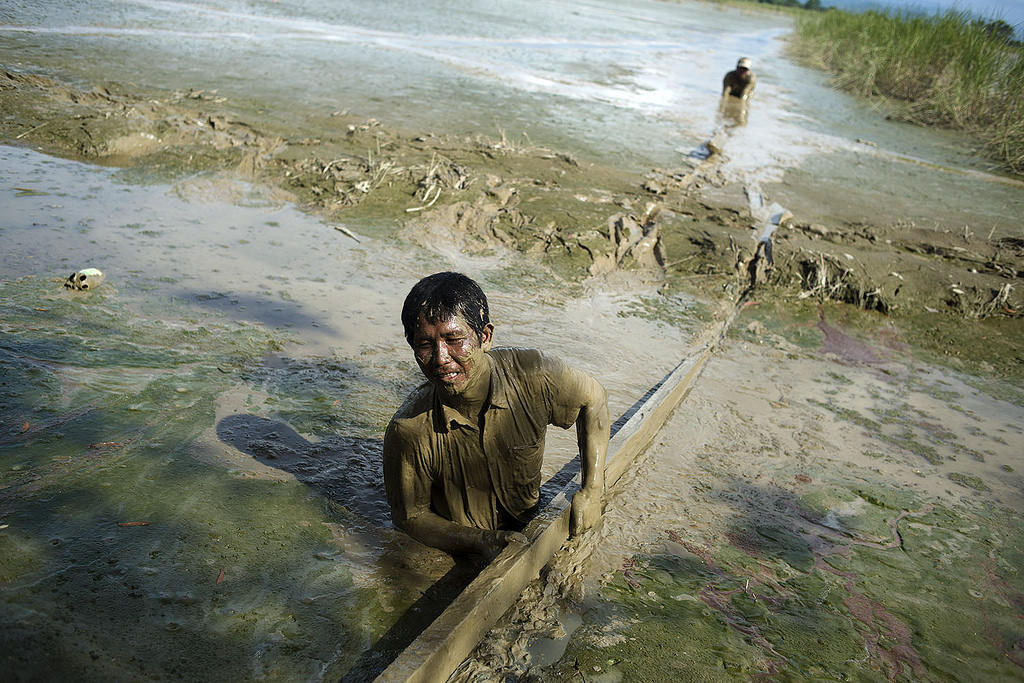 Myanmar 2015. Kalay. Aye Thar Yar village. Many areas are still badly affected on flooding, three weeks after the monsoon floods hit Myanmar´s northwest, western and south-western regions. Men in Kalay township area are rescuing boards from the flood water - the remaining pieces of their houses. 