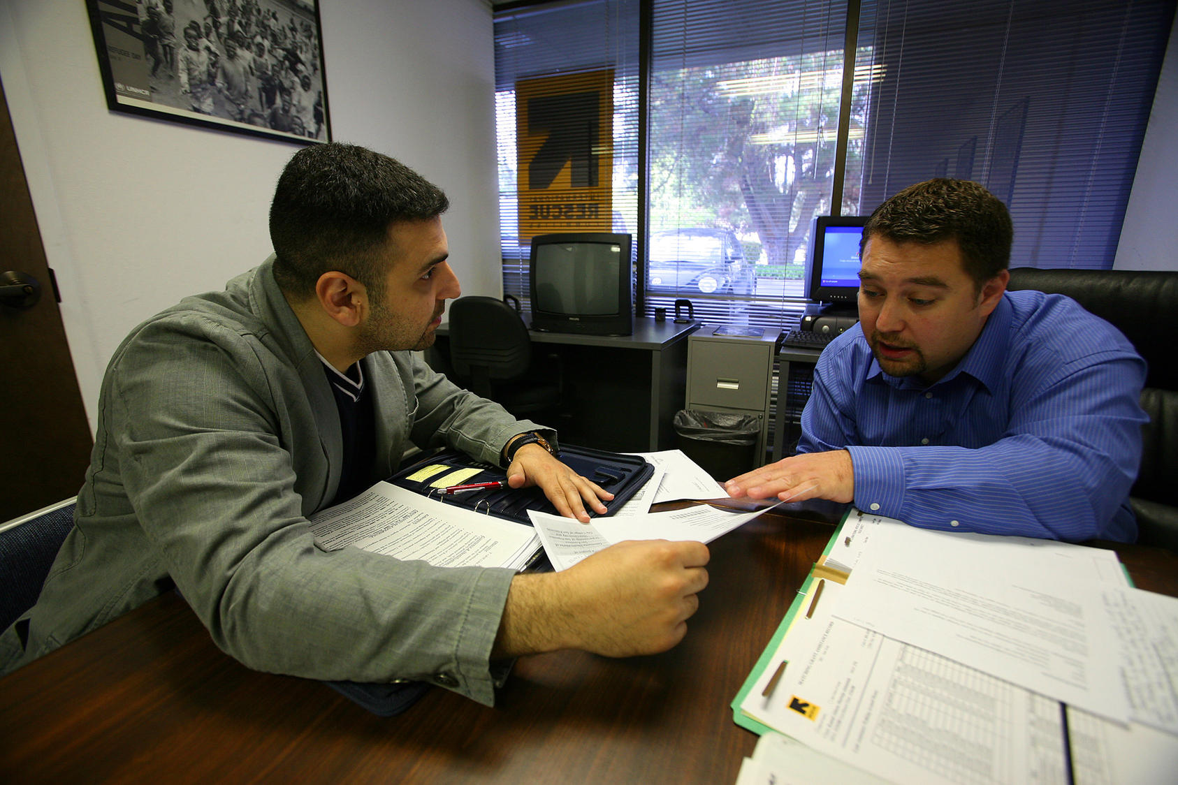 26-year-old Iraqi refugee, left, working on his resume with Sead Eminovic