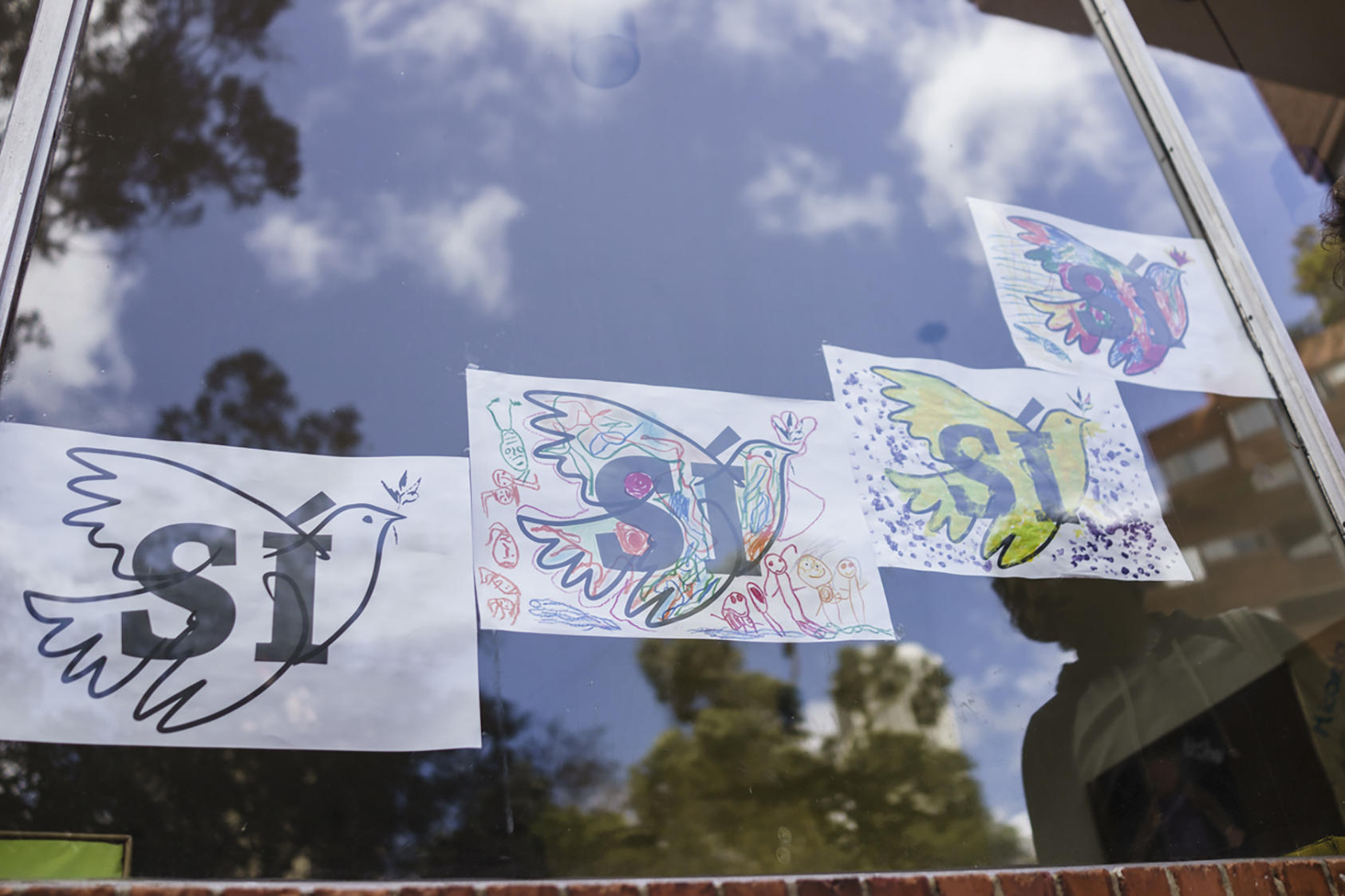 Artwork of doves with the Spanish word for "yes," urging support for a coming referendum, in the window of a kindergarten on the day of the signing of a peace agreement between the Colombian government and the Revolutionary Armed Forces of Colombia, or FARC, in Bogota, Sept. 26, 2016. In a moment that generations of Colombians yearned to see, the state and Marxist insurgents confirmed an accord to end a 52-year-old conflict, the last major war in the Americas. (Federico Rios Escobar/The New York Times)