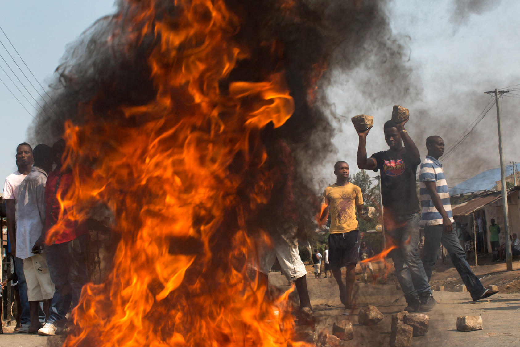 On election day, a crowd sets a fire and uses large cobblestones to make a roadblock in the Nyakabiga neighborhood after the body of an opposition activist was found dead in a ditch, in Bujumbura, Burundi, July 21, 2015. At several polling stations around Bujumbura, the capital, turnout was low Tuesday morning, with voters outnumbered by campaign workers and police officers. (Tyler Hicks/The New York Times) 