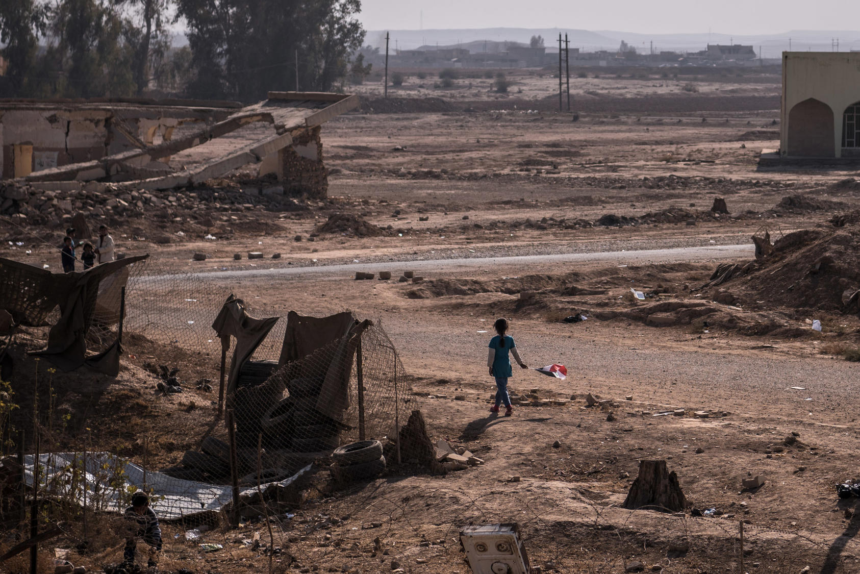 A girl with an Iraqi flag walks near her home in Qayyara, Iraq, Nov. 12, 2016. The military campaign to retake Mosul, Iraq’s second-largest city, has displaced nearly 70,000 Iraqis. More civilians than ever are taking the risk of evacuation, hoping to find help if they can make it past the militants’ gun range. (Sergey Ponomarev/The New York Times)