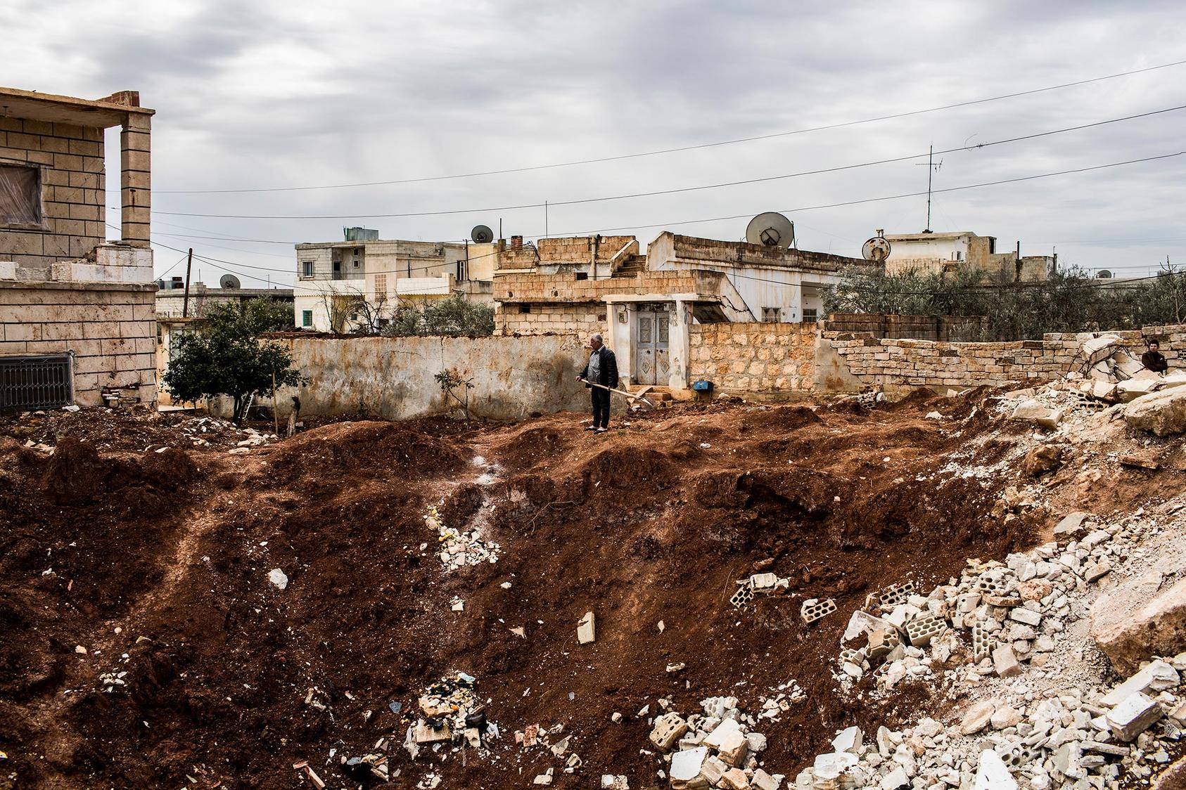  A man holding a shovel surveys a crater left by what locals said was a Scud missile strike 