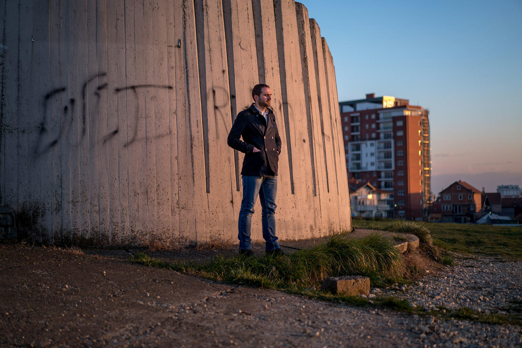 man standing outside prison wall in Pristina, Kosovo