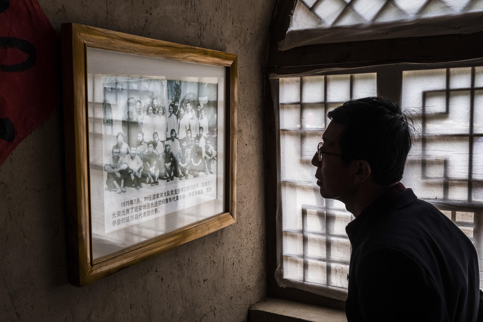 A visitor looks at a photo of a young Xi Jinping with party members, in Liangjiahe, China. The village, where Xi spent a formative period of his youth during the Cultural Revolution, has been converted into a tourist attraction. Photo NYT/Bryan Denton