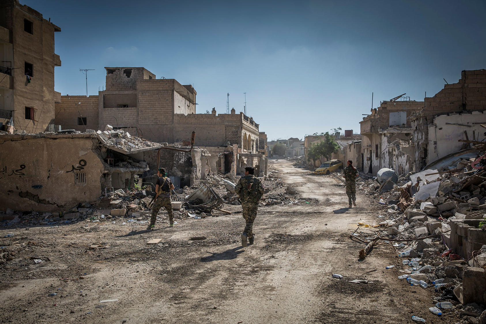 Soldiers with the Syrian Democratic Forces move through the destroyed streets of east Raqqa