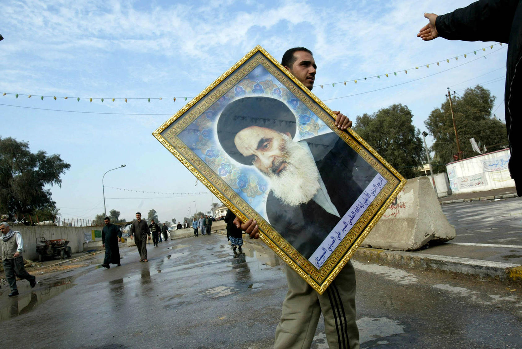An Iraqi with a portrait of Grand Ayatollah Ali-Sistani, Iraq's most influential religious leader
