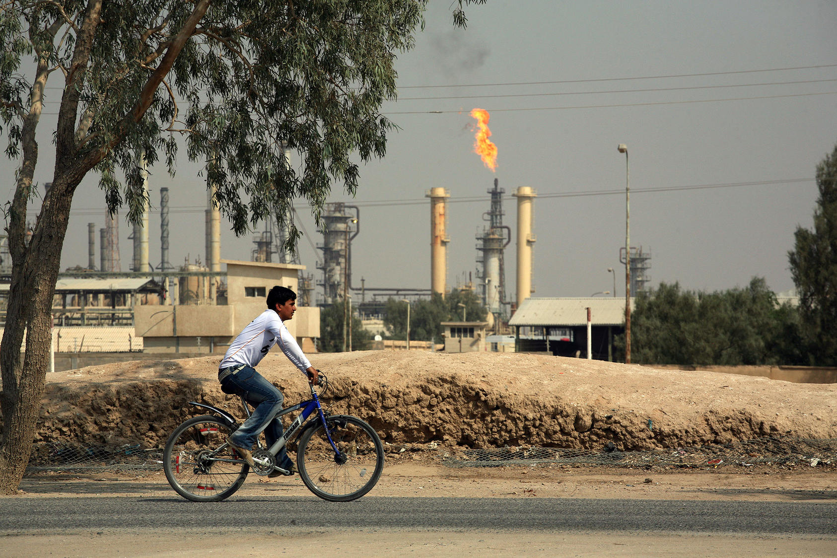 A bicyclist rides past a refinery near Basra, Iraq, on Oct. 27, 2009. (Joao Silva/The New York Times)