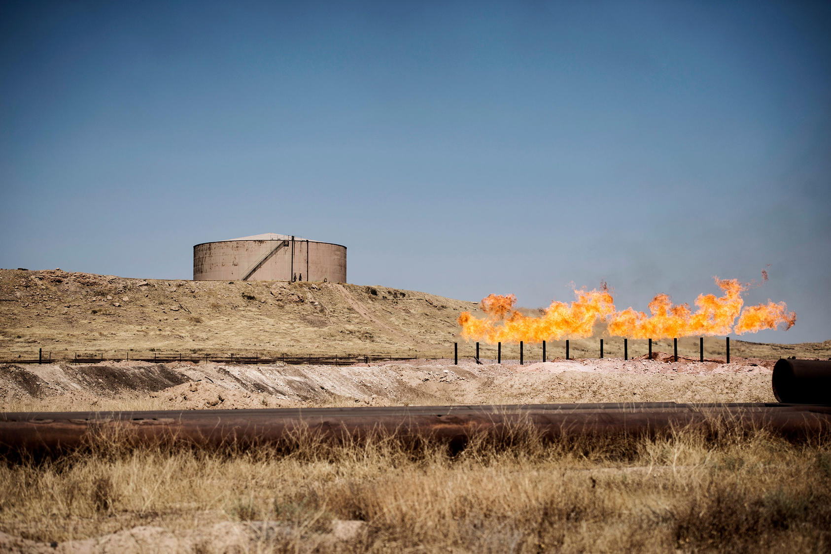 A gas flare burns near storage tanks in the oil fields near Kirkuk, Iraq