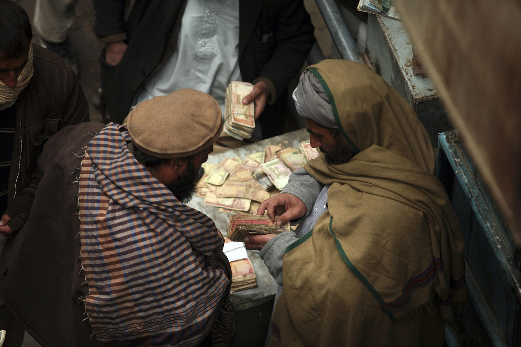 Men negotiate money exchanges at a market in Kabul. (Michael Kamber/The New York Times)