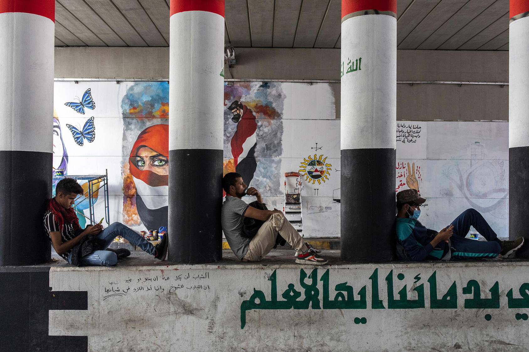 Antigovernment protesters sit in front of murals in Baghdad on Nov. 22, 2019.  (Ivor Prickett/The New York Times)