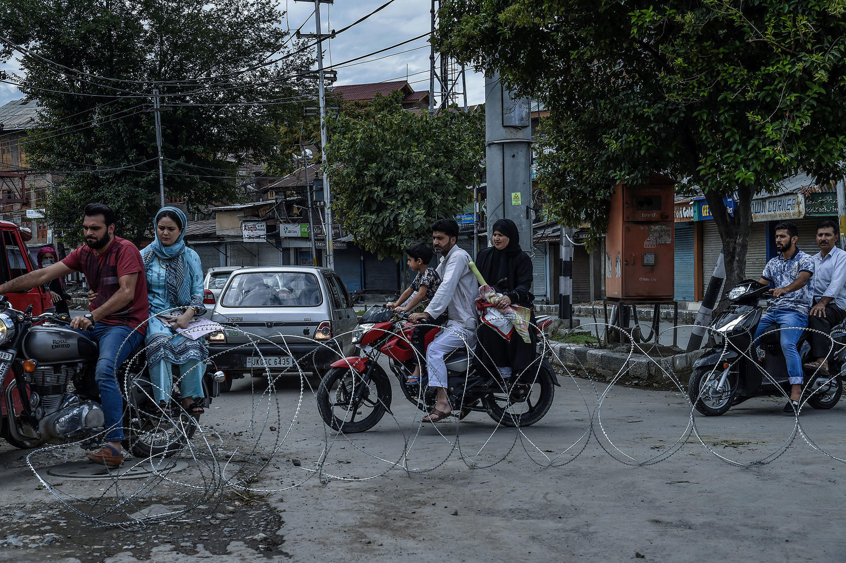 Motorcyclists navigate past barbed-wire placed by Indian security forces in the Kashmiri city of Srinagar on August 10, 2019. (Atul Loke/New York Times)