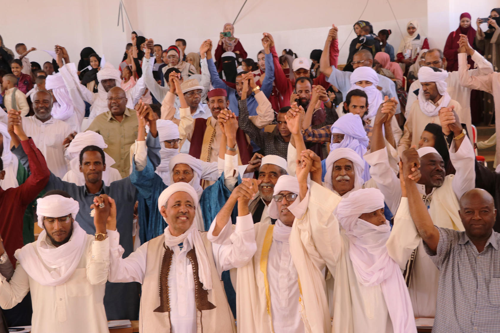 After signing a social pact against school violence, residents of the southern Libyan city of Ubari join hands during a USIP-sponsored Peace Day Celebration in September 2019. 