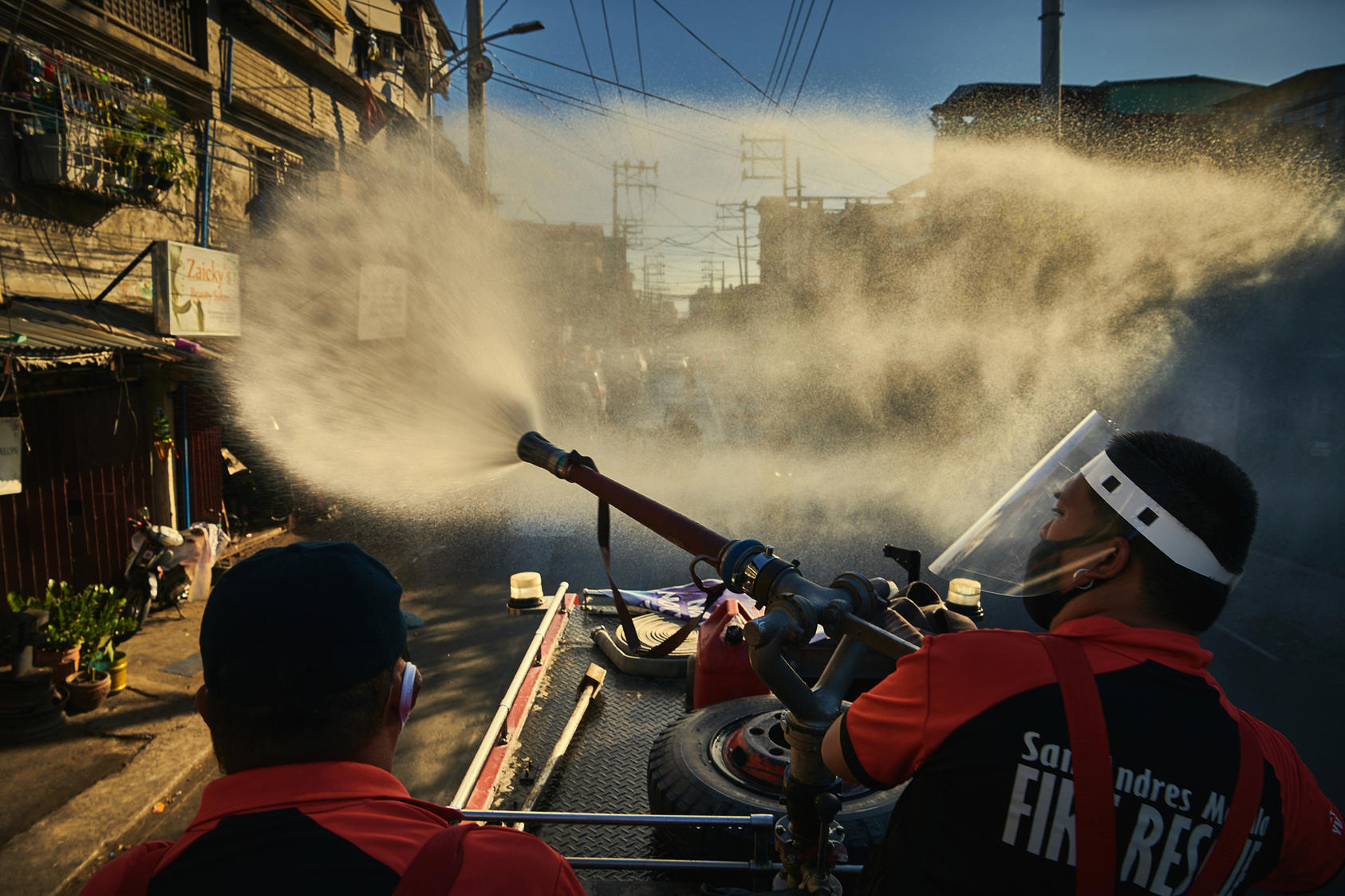 Firefighters spray disinfectant along a road in Manila, Philippines, on April 6, 2020, in an effort to keep the coronavirus from spreading. (Photo by Jes Aznar/New York Times)