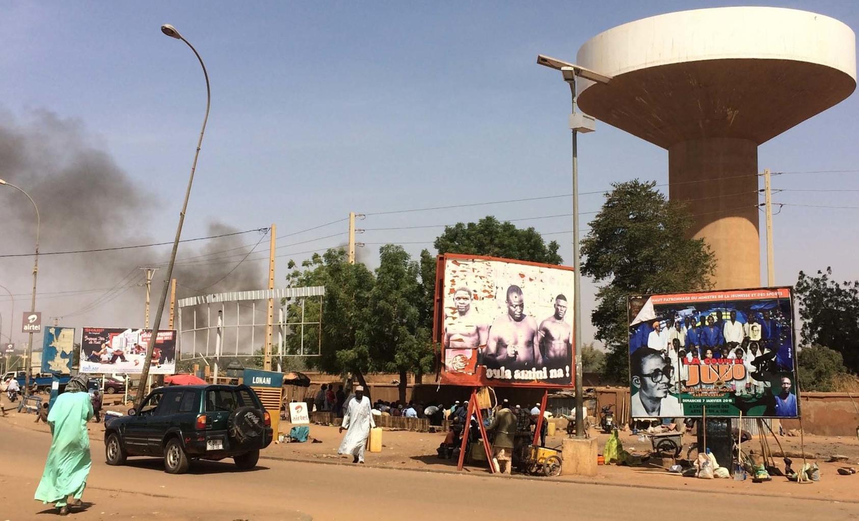 Men walk on the street or huddle in the shade of trees and billboards to eat lunch on a main street of Niamey V, one of the Nigerien capital’s poorest districts. Residents have improved security through community dialogues. (CC License 4.0/NigerTZai)