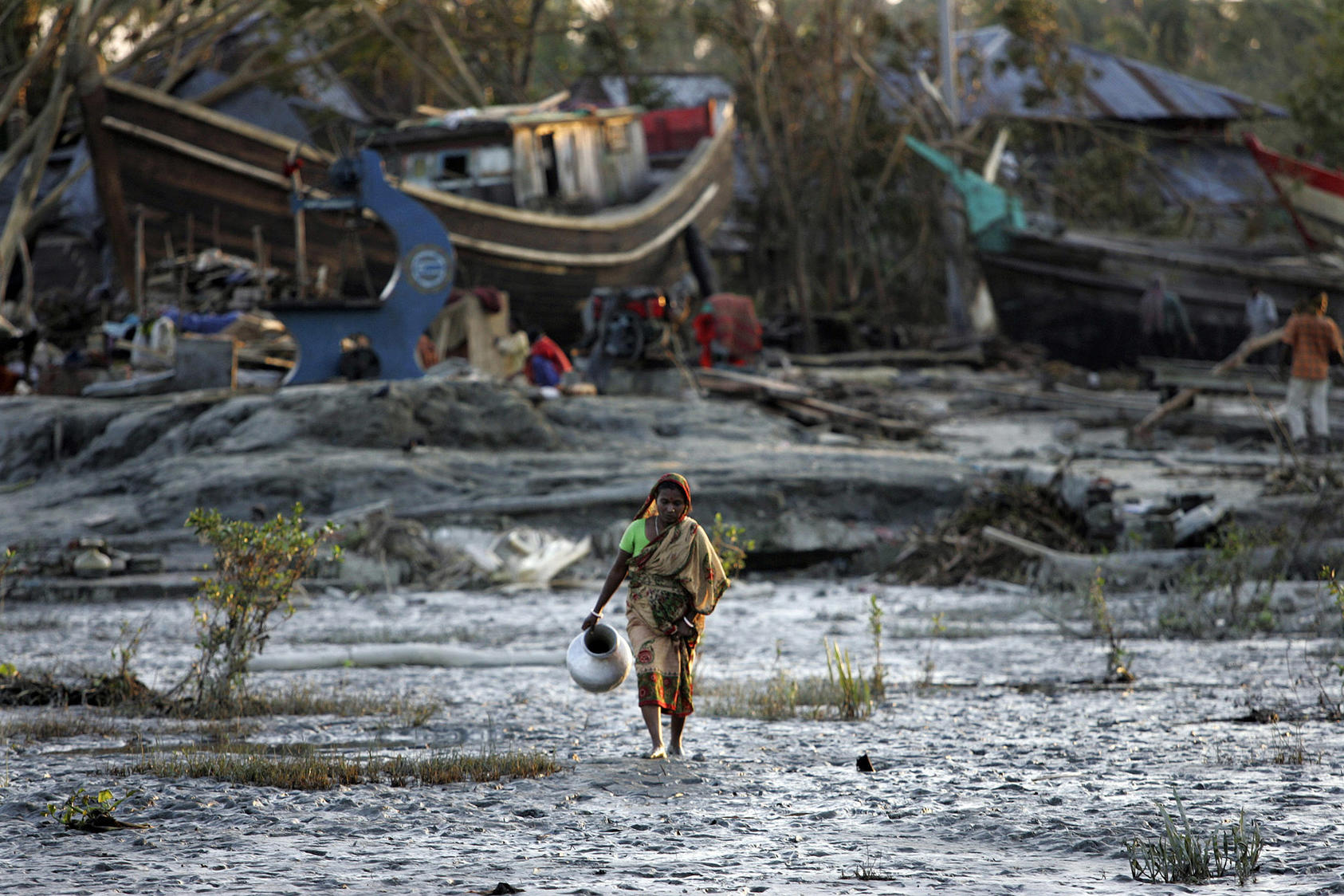 A woman walks through the mud and wreckage after a cyclone hit in the village of Khatachira, Bangladesh. November 20, 2007. (Ruth Fremson/The New York Times)