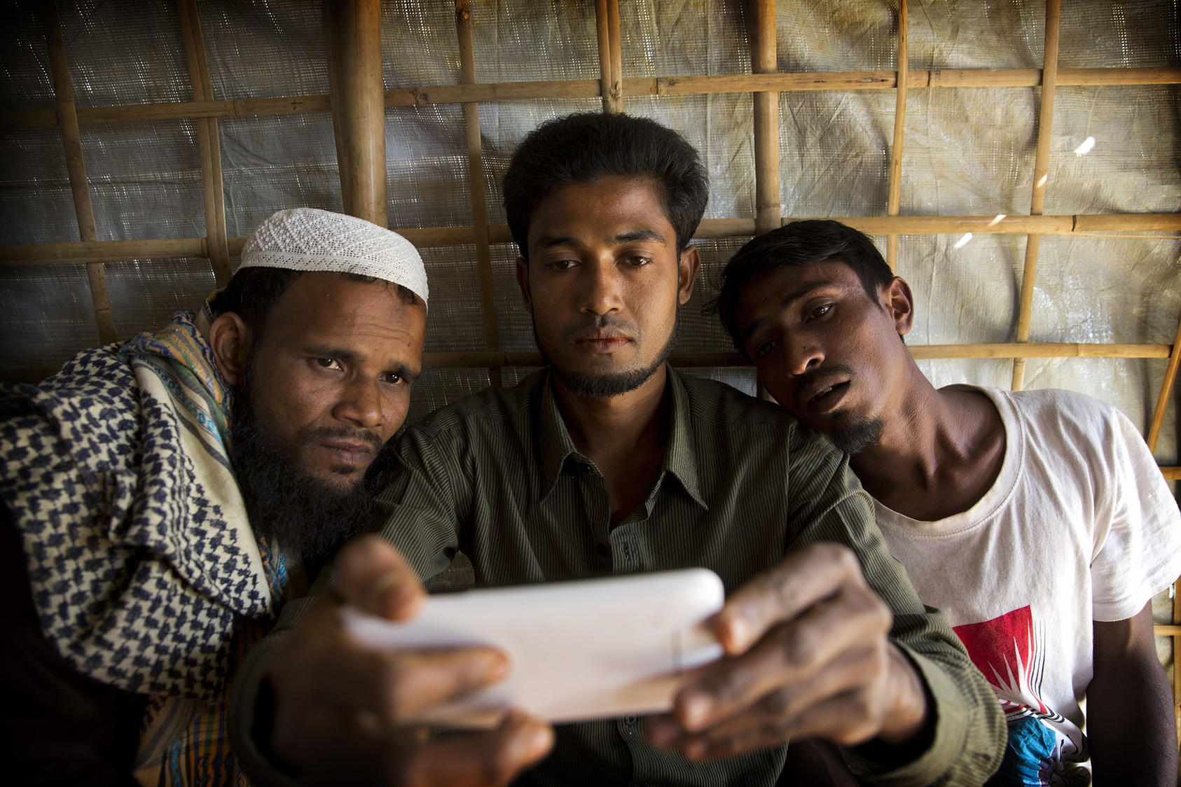 Refugiados musulmanes rohinyás miran un teléfono en Bangladés en enero de 2018. Las expresiones de odio sin restricciones en Facebook impulsaron la limpieza étnica en Birmania. (Fotografía de Manish Swarup/AP)