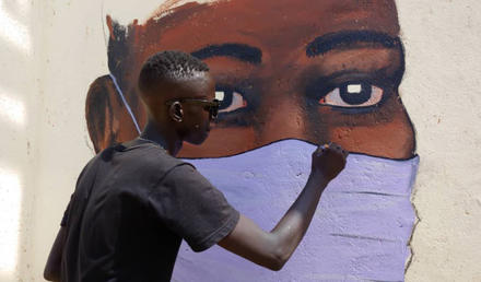 An artist paints one of many murals that civic activists use to win public support for efforts to halt COVID. (Anataban)