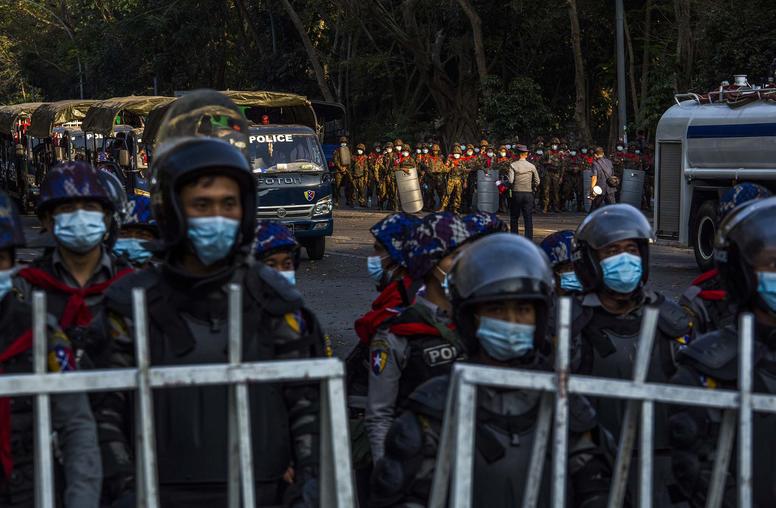Police and military forces stand by, as tens of thousands of people gather on University Avenue Road to protest against the military's seizure of power, Feb. 9, 2021, in Yangon, Myanmar. (The New York Times)