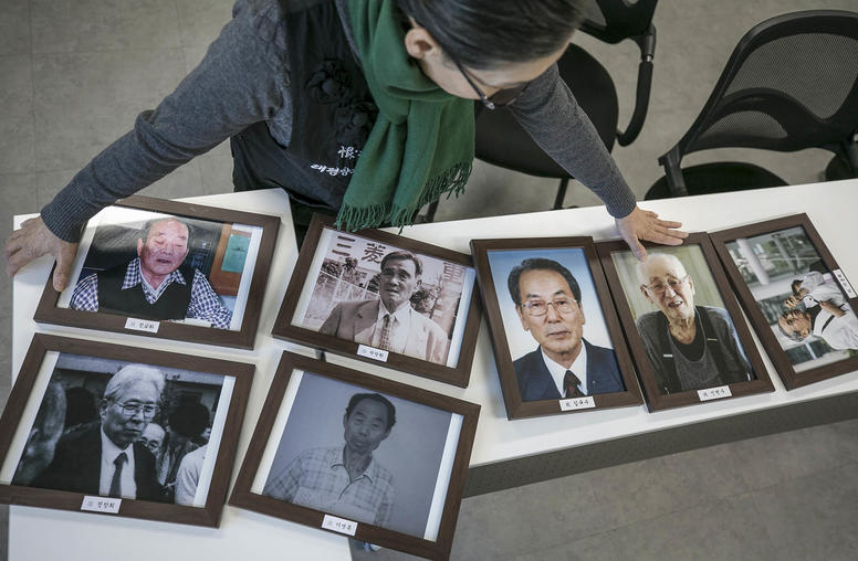 Lee Hee-ja, a South Korean activist whose father died as a forced laborer for the Japanese military, displays photos of other forced labor victims in Seoul, South Korea. December 7, 2018. (Jean Chung/The New York Times)