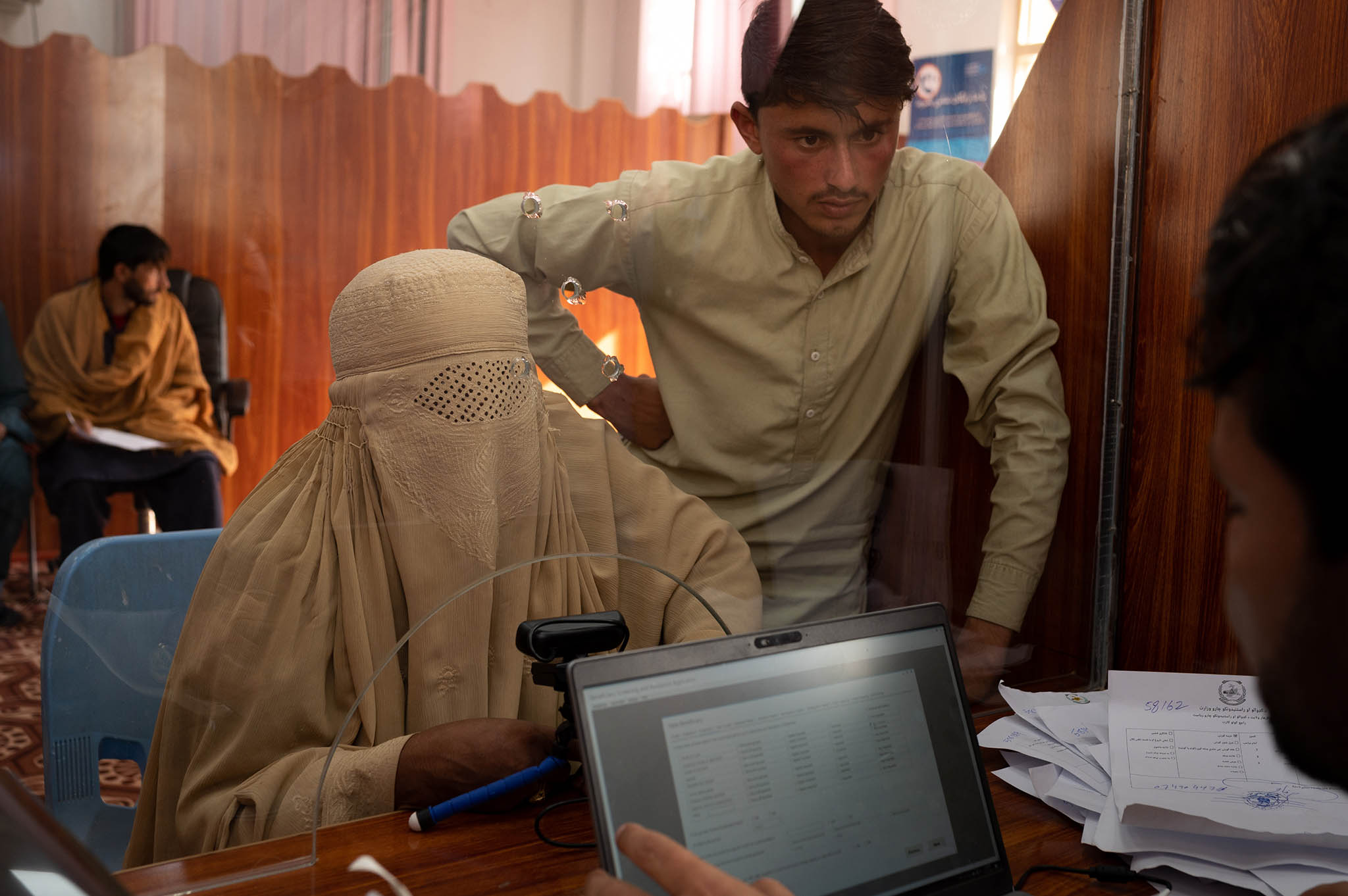 Barad Bibi, a widow, and her son Wahidullah register her family of seven for aid with the United Nations’ migration agency at the Torkham border crossing in eastern Afghanistan, Oct. 23, 2023. (Elise Blanchard/The New York Times)