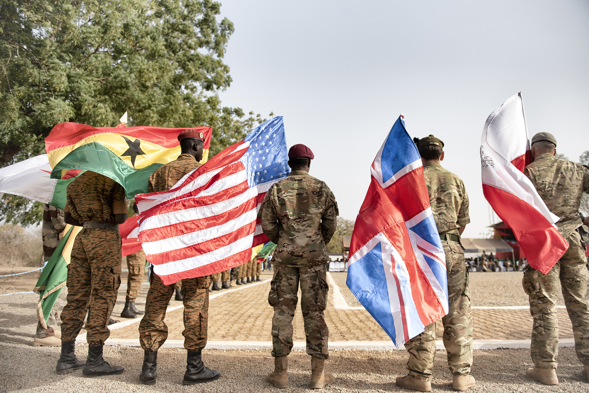 Soldiers hold flags in 2019 to open Flintlock, an annual U.S.-led counterterror exercise that is part of U.S. efforts to stabilize the Sahel. Analysts urge a broader strategy to improve governance in the region. (Laetitia Vancon/The New York Times)