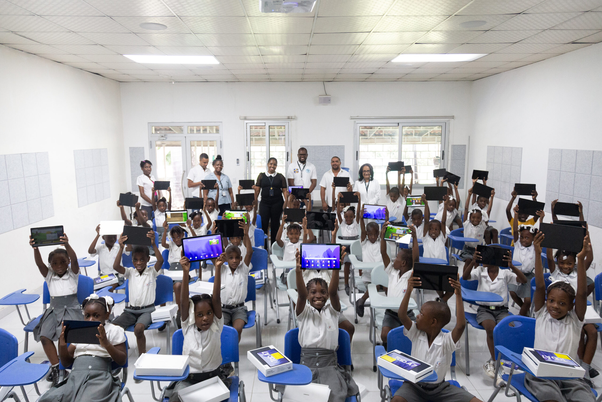 Dr. Deschamps and staff of the civic group GHESKIO join pupils who celebrate receiving tablet computers for their studies. Such Haitian civil society groups are strong partners with international peacebuilding efforts. (Haitian Global Health Alliance)