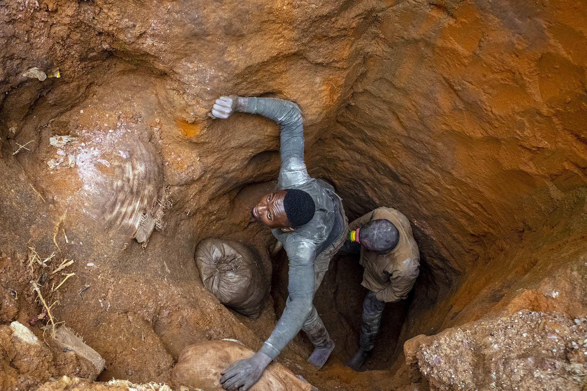 Jose Bumba, left, pulls a 220-pound bag of cobalt from a makeshift mine in Kasulo, the Democratic Republic of the Congo, on April 26, 2021. (Ashley Gilbertson/The New York Times)]