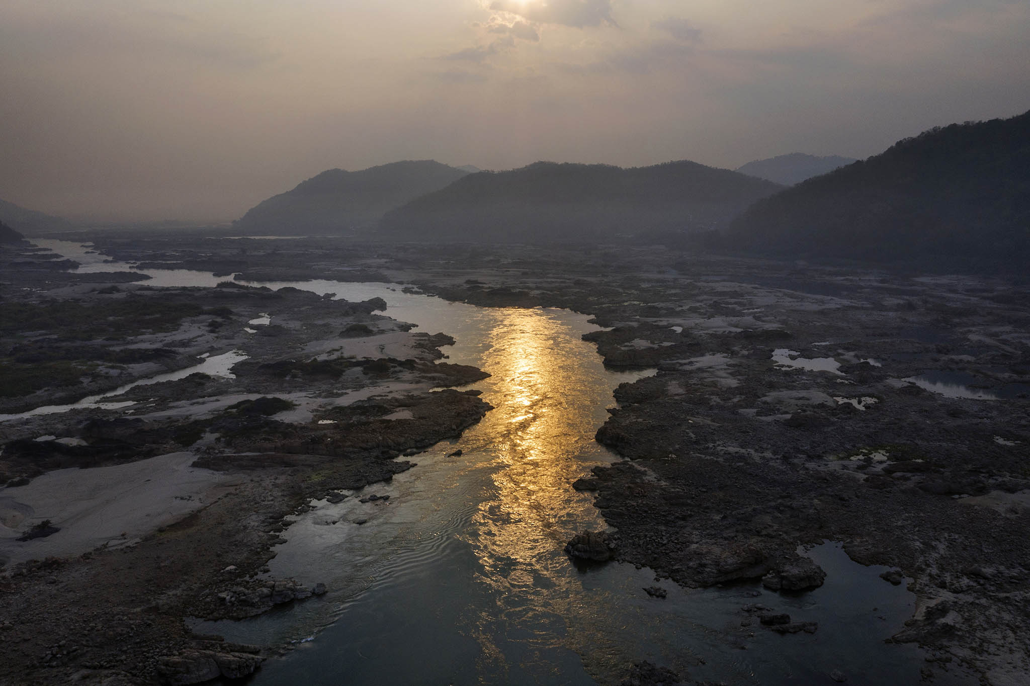 A narrowed Mekong River flows through the center of its partially dried out riverbed near Sangkhom, Thailand. January 25, 2020. (Adam Dean/The New York Times)