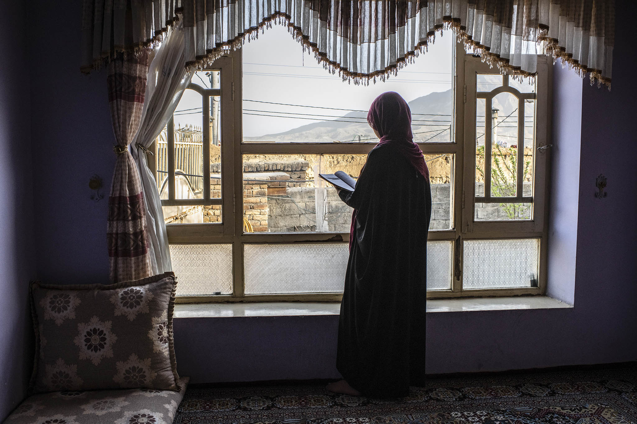 A female high school student stands in her home in Kabul, Afghanistan, on March 28, 2022. The Taliban has banned women and girls from attending school. (Bryan Denton/The New York Times)