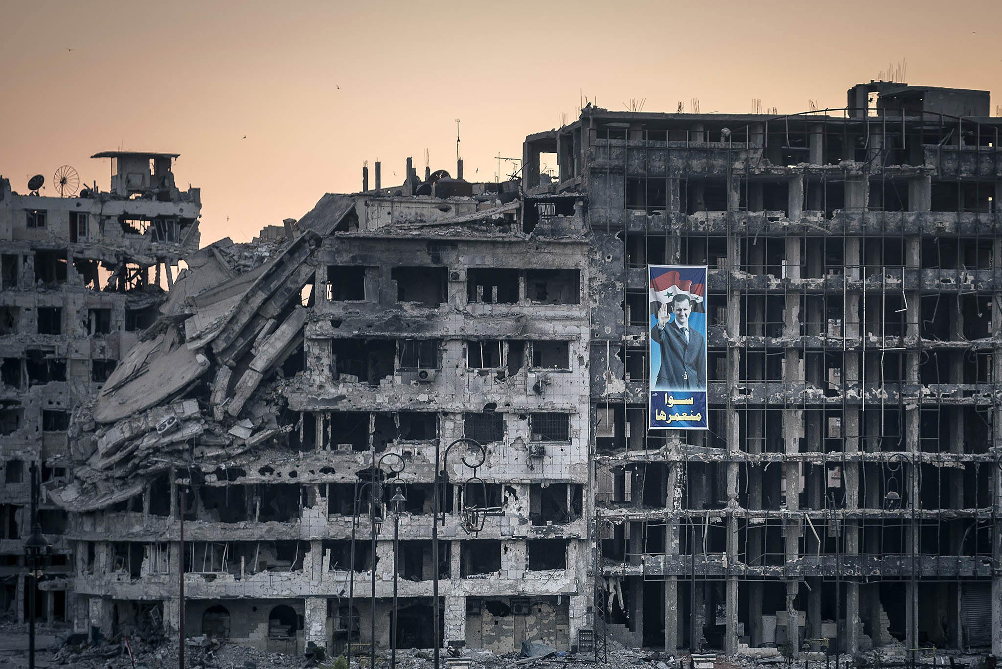 A poster for Syria’s President Bashar al-Assad hangs on a destroyed shopping mall in the war-ravaged city of Homs, Syria, June 15, 2014. (Sergey Ponomarev The New York Times)