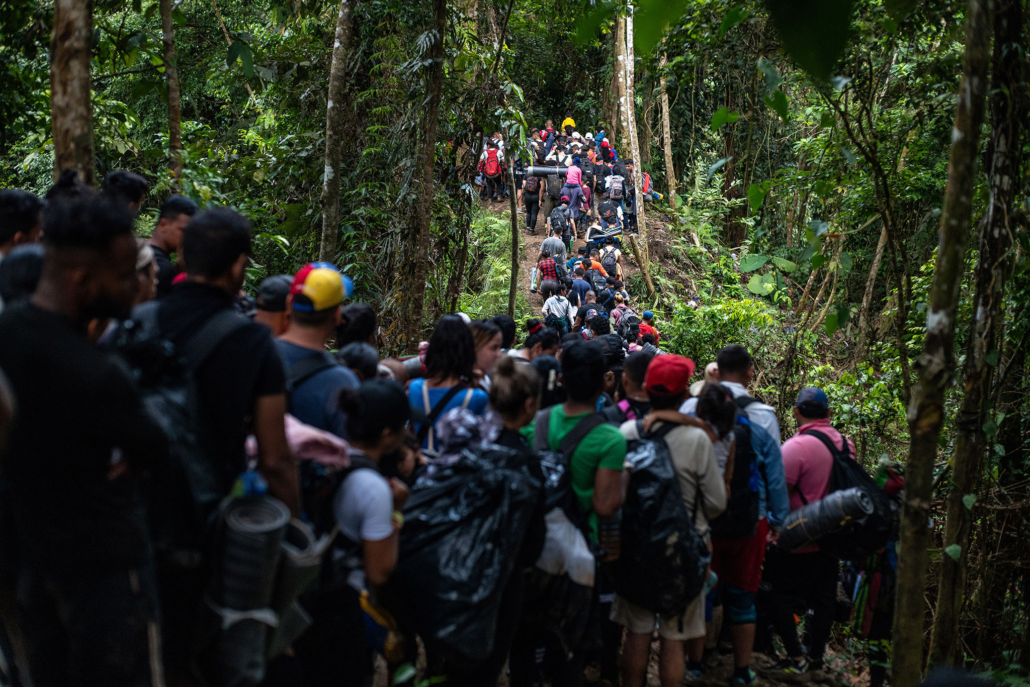 Un grupo de migrantes cruza un río en el Tapón del Darién, el estrecho tramo de selva que conecta Colombia y Panamá. 3 de agosto de 2023. (Federico Rios/The New York Times)