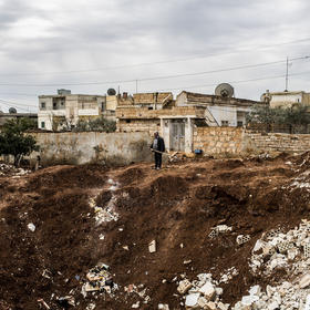 A resident of Syria’s Idlib province surveys a crater from a missile strike in 2013. As the province faces a new offensive, its nascent women’s movement has had to close some of its education centers for women and girls. (Bryan Denton/The New York Times)