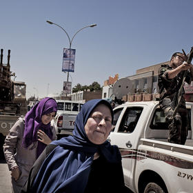 Women in Benghazi pass armed police and soldiers in a city street. Urban women include civic activists, and rural women include traditional tribal mediators, who work to halt fighting. (Tomas Munita/The New York Times)
