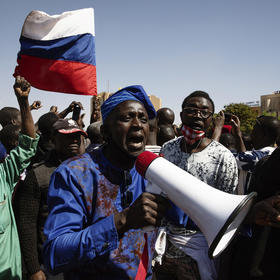 Men support Burkina Faso’s January coup with a Russian flag—a jab at France amid anger at insecurity under the prior civilian government, backed by French forces. Most Burkinabe citizens reject coups in research surveys. (Malin Fezehai/The New York Times)