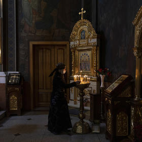 A woman lights a candle at the Holy Transfiguration Cathedral in Vinnytsia, Ukraine. March 12, 2022. (Ivor Prickett/The New York Times)