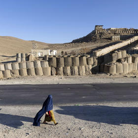 A woman walks along the side of the Kabul–Kandahar Highway north of Ghazni, Afghanistan, in Dec. 8, 2021. (David Guttenfelder/The New York Times)