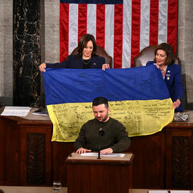 Vice President Kamala Harris, left, and House Speaker Nancy Pelosi, right, show a Ukrainian flag that presented to them by President Volodymyr Zelenskyy, center, as he addressed Congress yesterday. (Kenny Holston/The New York Times)