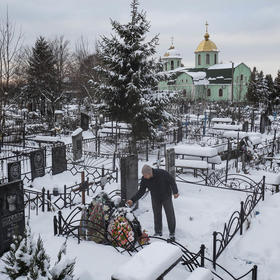 Yuriy Kryvenko at the grave of his father, one of hundreds of civilians killed by Russian troops at Bucha, near Kyiv, in 2022. Advocates for the rule of law demand prosecution of crimes as part of an end to the war. (David Guttenfelder/The New York Times)
