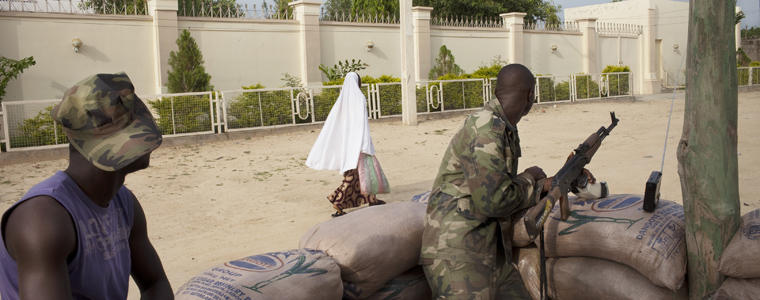 Nigerian soldiers survey passing civilians in the government reserved area of Maiduguri, in north-eastern Nigeria, July 19, 2011. An Islamist insurgency that has haunted northern Nigeria appears to be branching out and collaborating with al-Qaida's affiliates, alarming Western officials and analysts who had previously viewed the militants here as a largely isolated, if deadly, menace. (Samuel James/The New York Times)