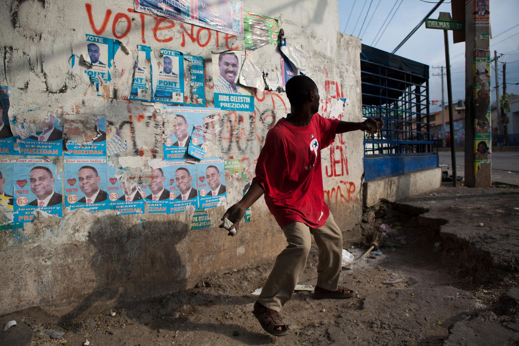 A protester hurls a rock at United Nations peacekeepers outside the electoral board offices in Port-au-Prince, Haiti, on Dec. 8, 2010. Angry protesters torched the headquarters of the government-backed presidential candidate and blocked streets with rubble from earthquake-destroyed buildings hours after the late-night release of preliminary election results triggered violence and new questions about vote rigging.