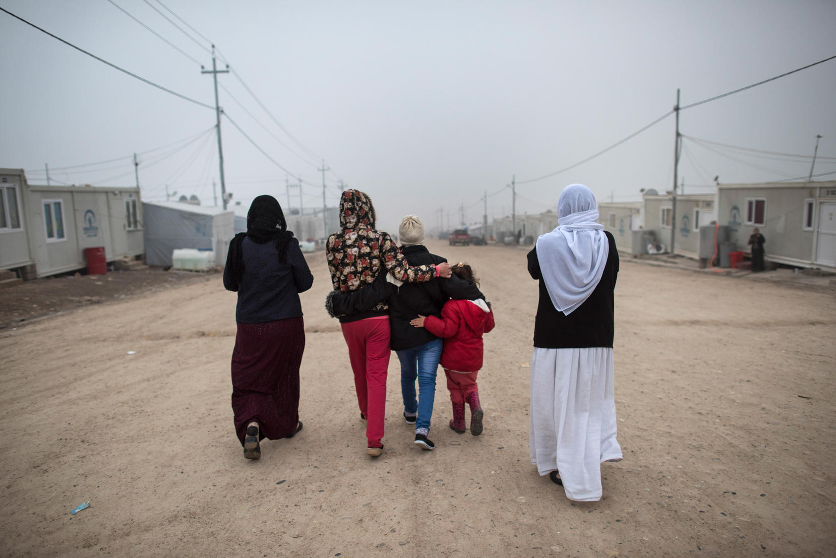 “M.”, center, a Yazidi teen who escaped sex slavery under the Islamic State group, is comforted by relatives before leaving to be resettled in Germany, at a camp near Dohuk, Iraq, Jan. 24, 2016. Islamic State leaders have made sexual slavery integral to the group’s operations, aggressively pushing birth control on the victims to keep the trade running. (Lynsey Addario/The New York Times)