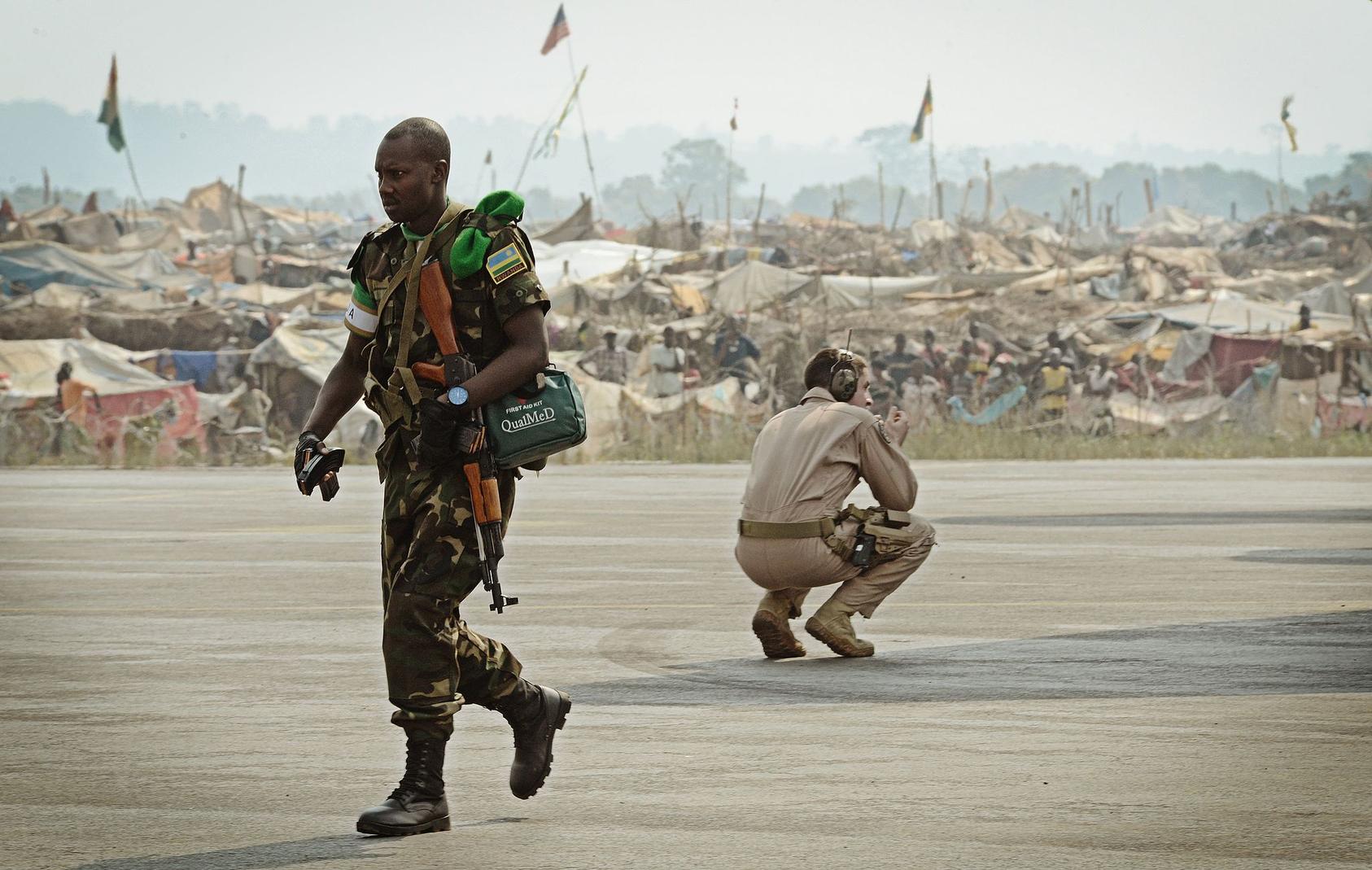 An African Union soldier and U.S. airman share the tarmac of the Central African Republic’s main airport as refugees from the CAR’s war watch peacekeepers’ arrival in 2014. Photo courtesy of DIMOC/SSgt Ryan Crane