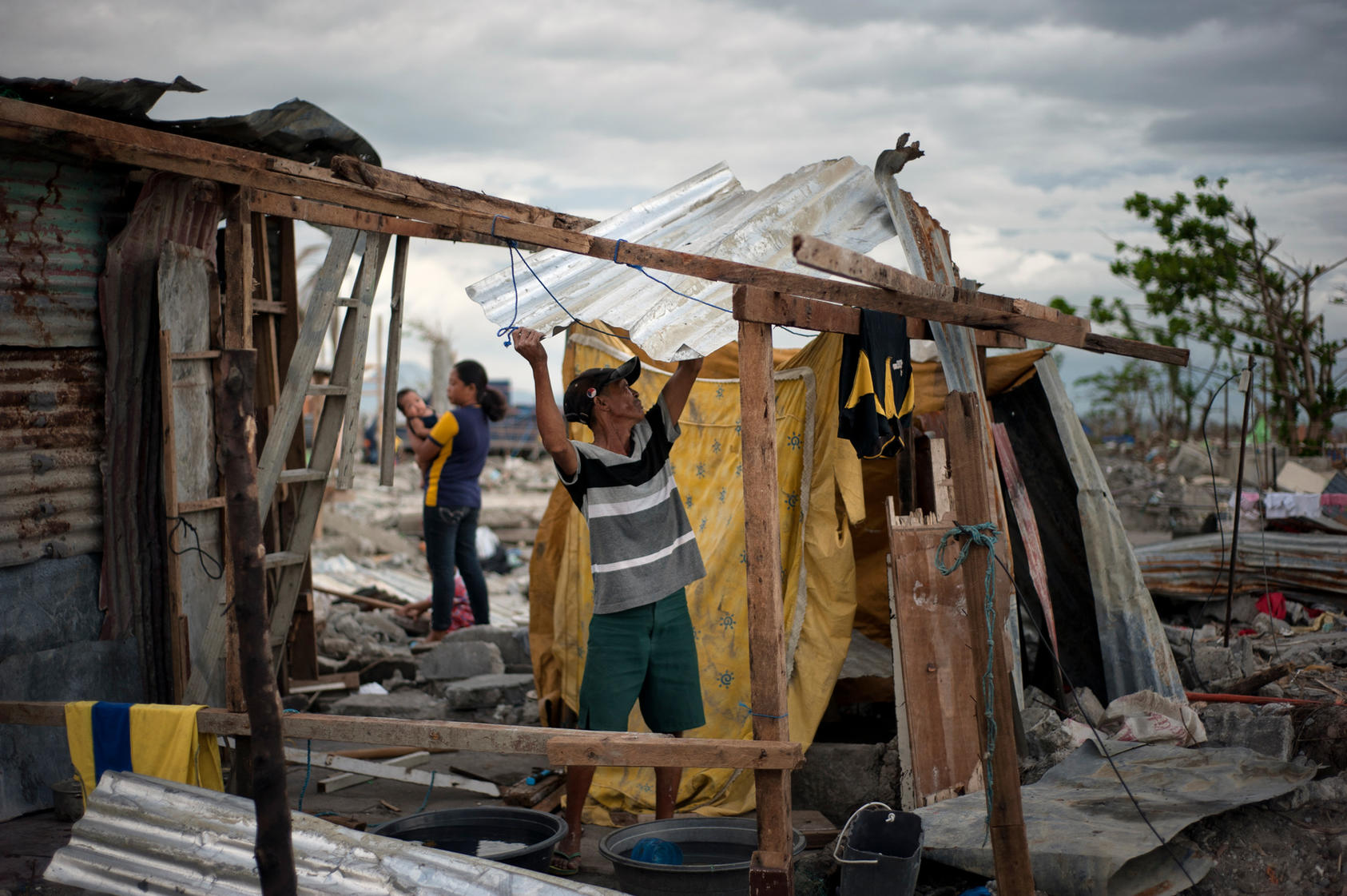 A typhoon victim erects a makeshift house for shelter in Barangay 88, a small coastal village in Tacloban, Philippines, Dec. 7, 2013. Land disputes in settlements and shantytowns up and down the coast are among the many reasons the recovery effort in the area is faltering.