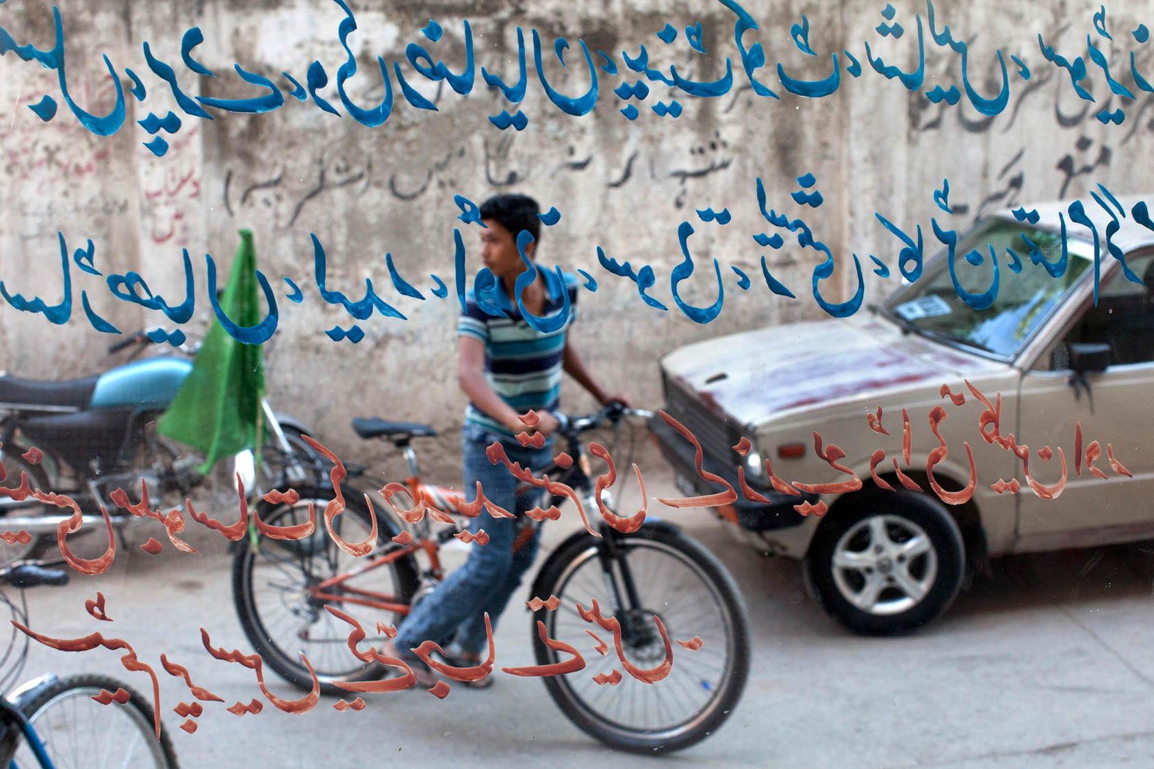 A youth displays his support for the Muslim League with a green flag on his bicycle, as seen through the window of a shop, in Rawalpindi, Pakistan, May 8, 2013. General elections in Pakistan are scheduled to be held on Saturday to elect a new parliament.