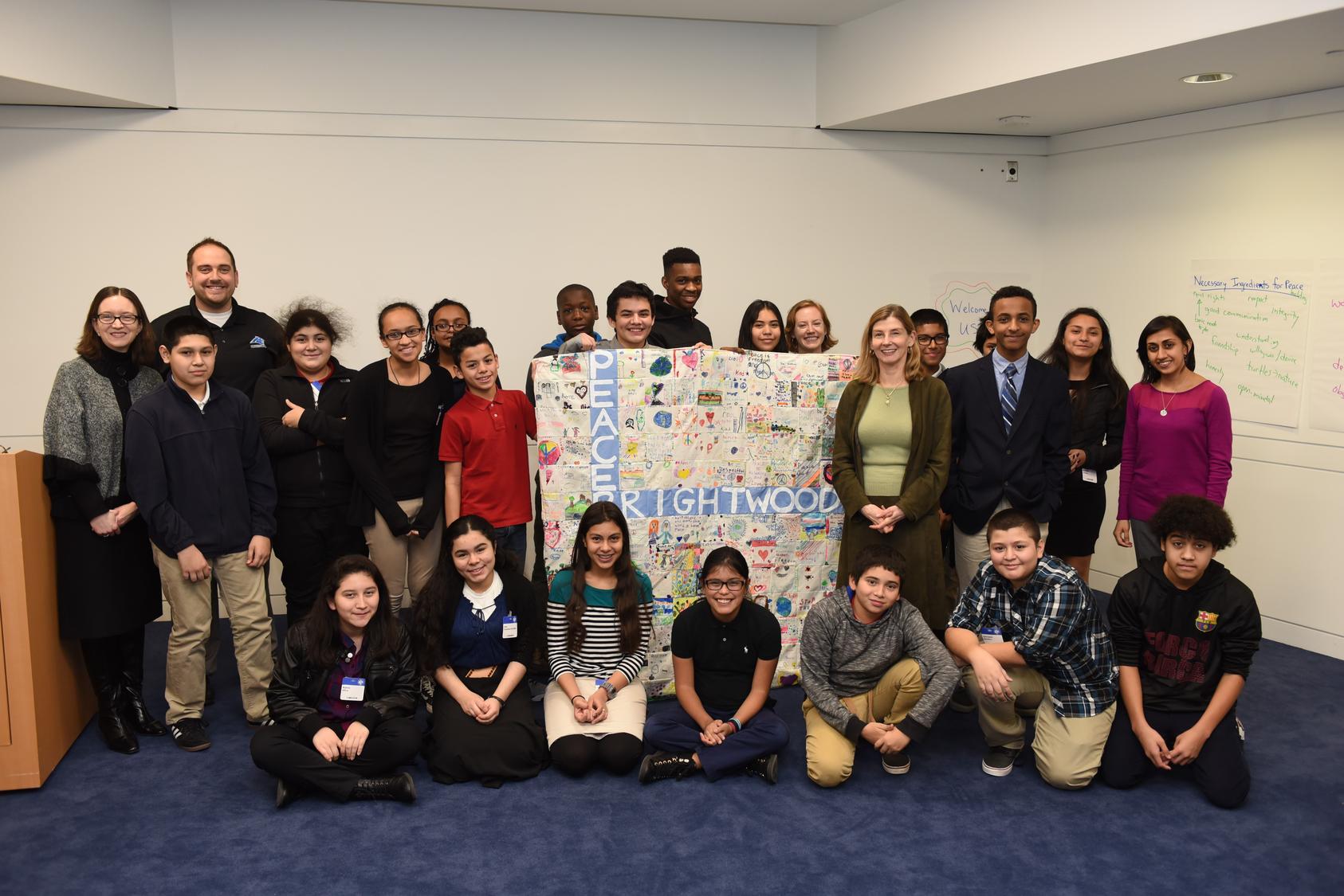 Brightwood Education Campus students, along with Monica Shah and Assistant Principal Justin Ralston, present USIP President Nancy Lindborg with a Peace Quilt following a workshop at USIP.