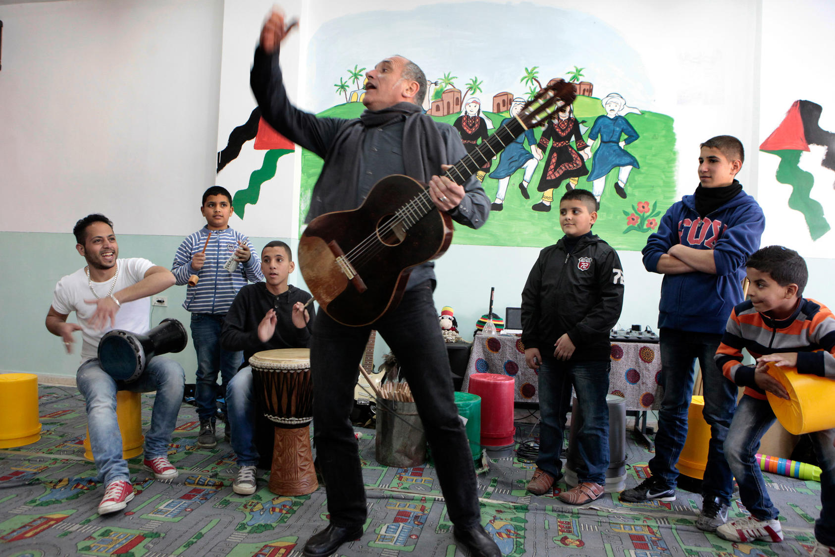 David Broza, an Israeli singer-songwriter, leads a workshop with Palestinian boys in the Shuafat neighborhood of East Jerusalem, Jan. 3, 2014. Broza visits here regularly as part of a personal effort to bridge the Israeli-Palestinian divide. Of his outlook on the peace process, Broza has said “There has to be a generation that will plant the seeds, and there will be those that will sit in the shade, and those that will eat the fruit.”