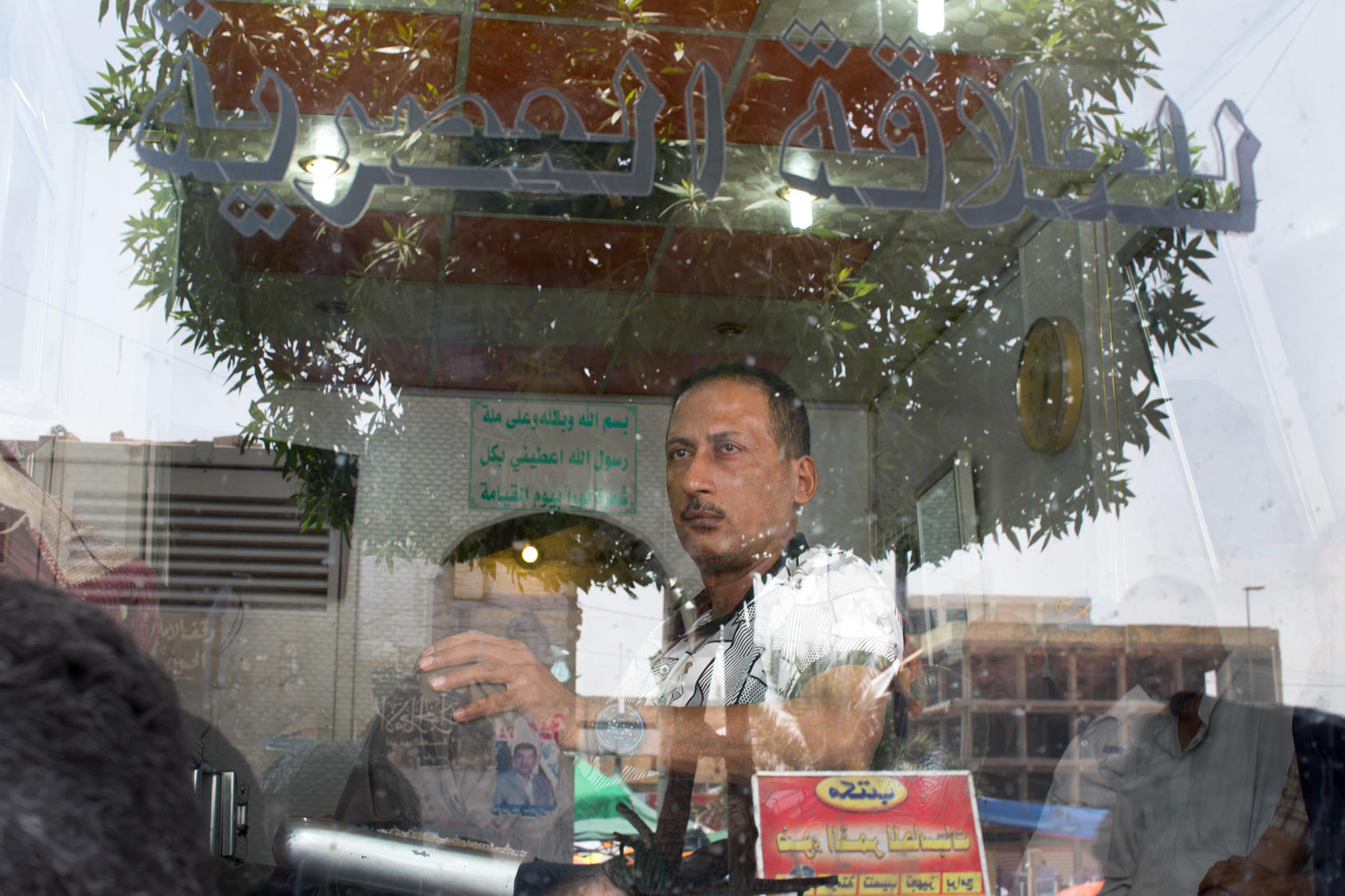 A man watches from inside a barber shop as Iraqi Shiites gather for prayer in the Sadr City district of Baghdad.
